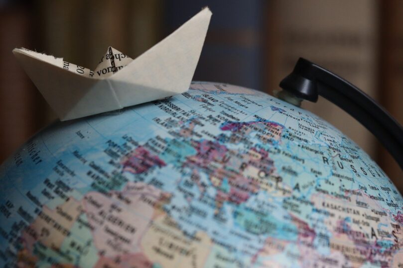 Paper boat on top of a globe symbolising international career journey